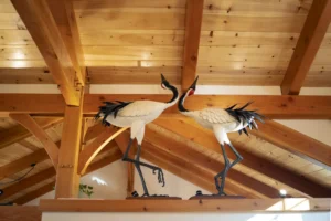 A statue of two herons set against a timber frame ceiling.