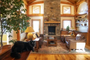 A timber frame great room with a fireplace and a cat.