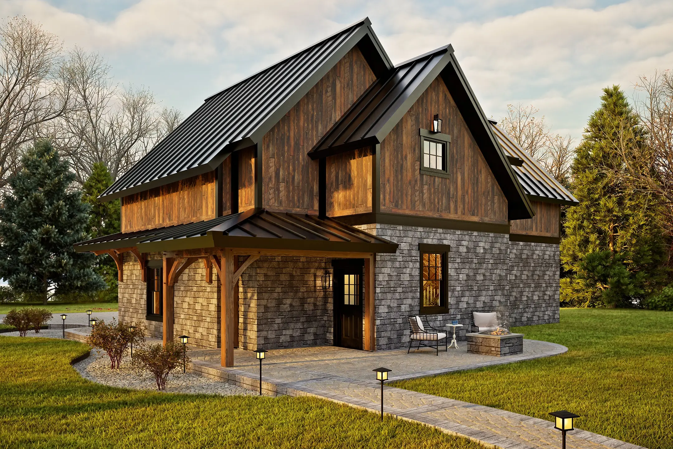 Side view of the BronsonV2 timber-frame home showcasing its blend of stone masonry, vertical wood siding, and a sleek black metal roof. A covered entry porch with timber posts leads to a dark wooden door. Nearby, a small patio with cushioned chairs and a stone fire pit sits beside a landscaped walkway. Mature trees and trimmed lawn surround the structure, highlighting its rustic-modern appeal.