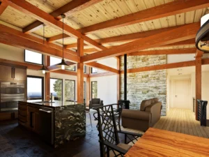 Interior view of the CreekRock V2 mountain modern timber frame home showcasing exposed wood beams, modern kitchen with stone backsplash and island, freestanding wood stove, hardwood flooring, and large windows bringing in natural light.