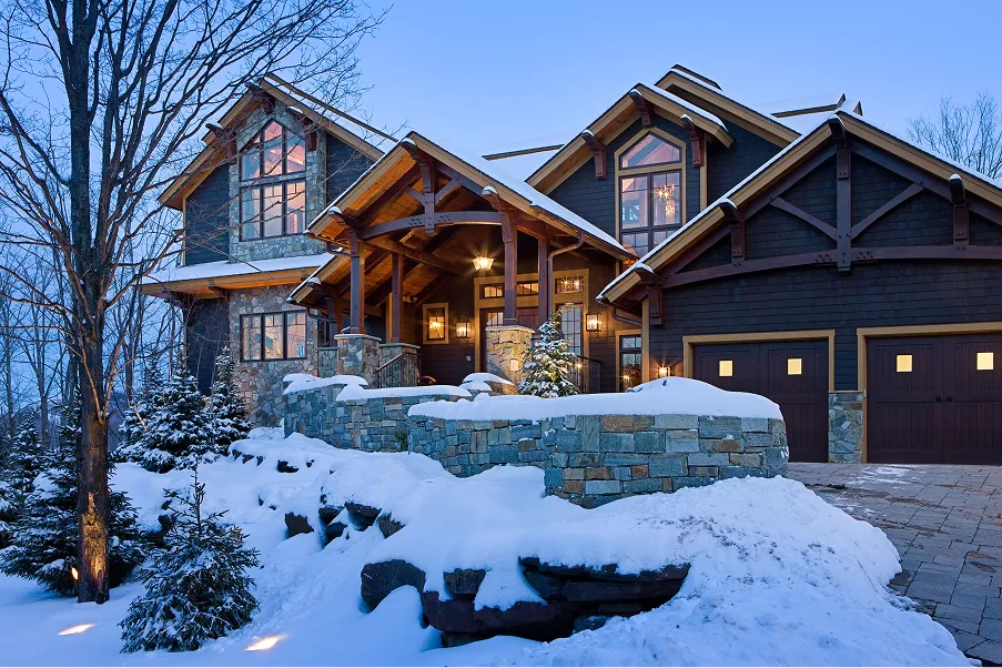 Luxury timber frame home with stone accents and exposed beams in a snowy mountain setting, ideal for Eagle Rock Resort lot owners seeking a four-season retreat.