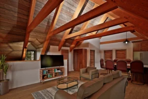 Open-concept interior living space with exposed timber trusses, vaulted ceiling, seating area, television space, and kitchen within the Shelburne V2 carriage house.