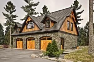 Exterior perspective of the Shelburne V2 carriage house highlighting three carriage-style garage doors, stone masonry, timber detailing, and steep rooflines.
