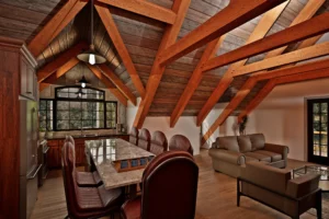 Interior of the Shelburne V2 timber frame carriage house featuring exposed kingpost trusses, vaulted ceiling, kitchen island seating, and open living area.