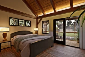 Primary bedroom in the Palmetto Sanctuary with exposed timber beams, a vaulted wood ceiling, large windows, and a glass door opening to a screened porch.