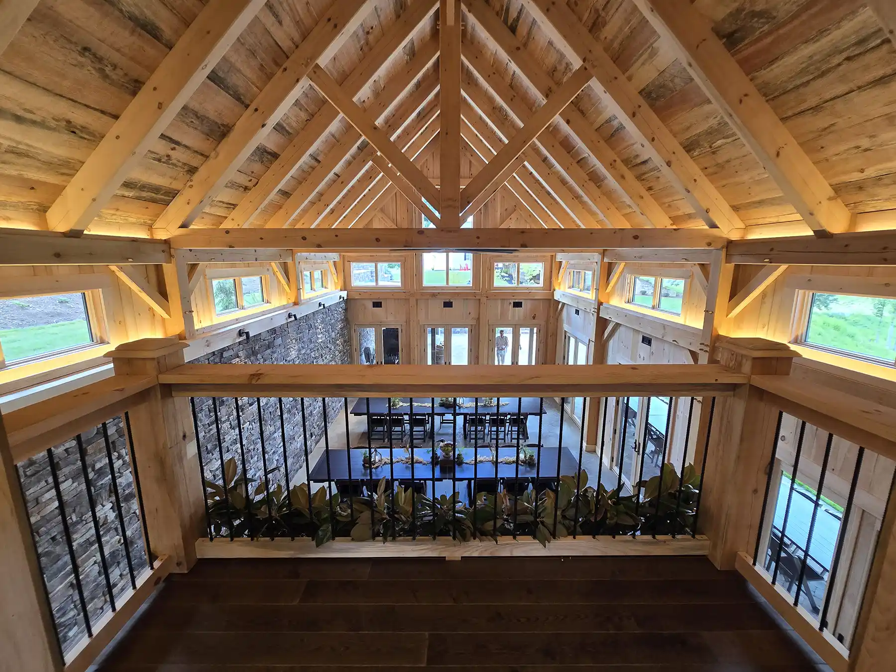 Upper-level view overlooking the main gathering space at the Oak & Vine Event Center, highlighting the exposed timber frame structure and vaulted roof.